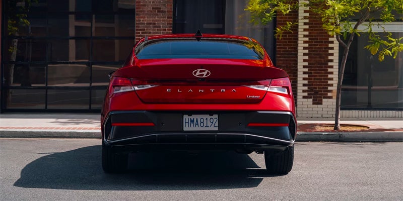 Rear view of a red 2024 Hyundai ELANTRA N parked, showcasing its compact design and distinctive taillights.