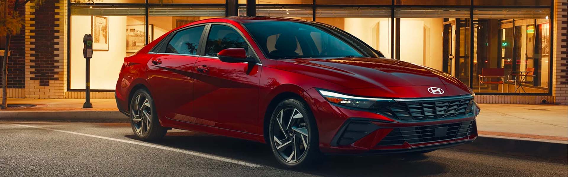 Red Hyundai Elantra Hybrid parked on the street during the evening next to a big building
