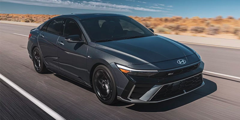 Black Hyundai Elantra driving down the road at high speed